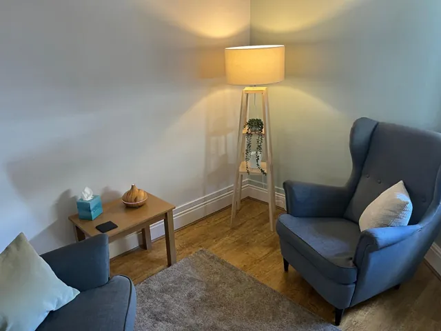 Two upholstered armchairs with a wooden tripod lamp and side table