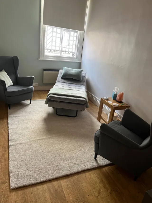 A reclining couch and armchairs beside a window at Calm Collective