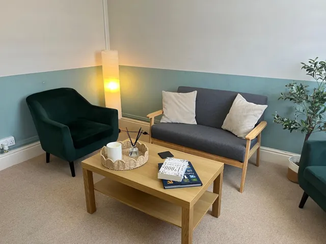 Grey sofa and green armchairs around a wooden coffee table
